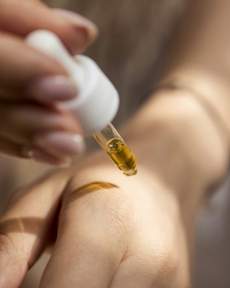 Serum dropper releasing a golden drop onto skin