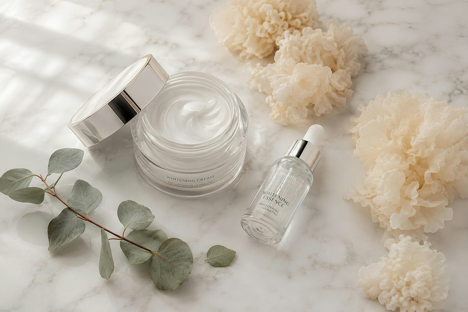 Jar of moisturising cream with a serum bottle and eucalyptus on a marble surface