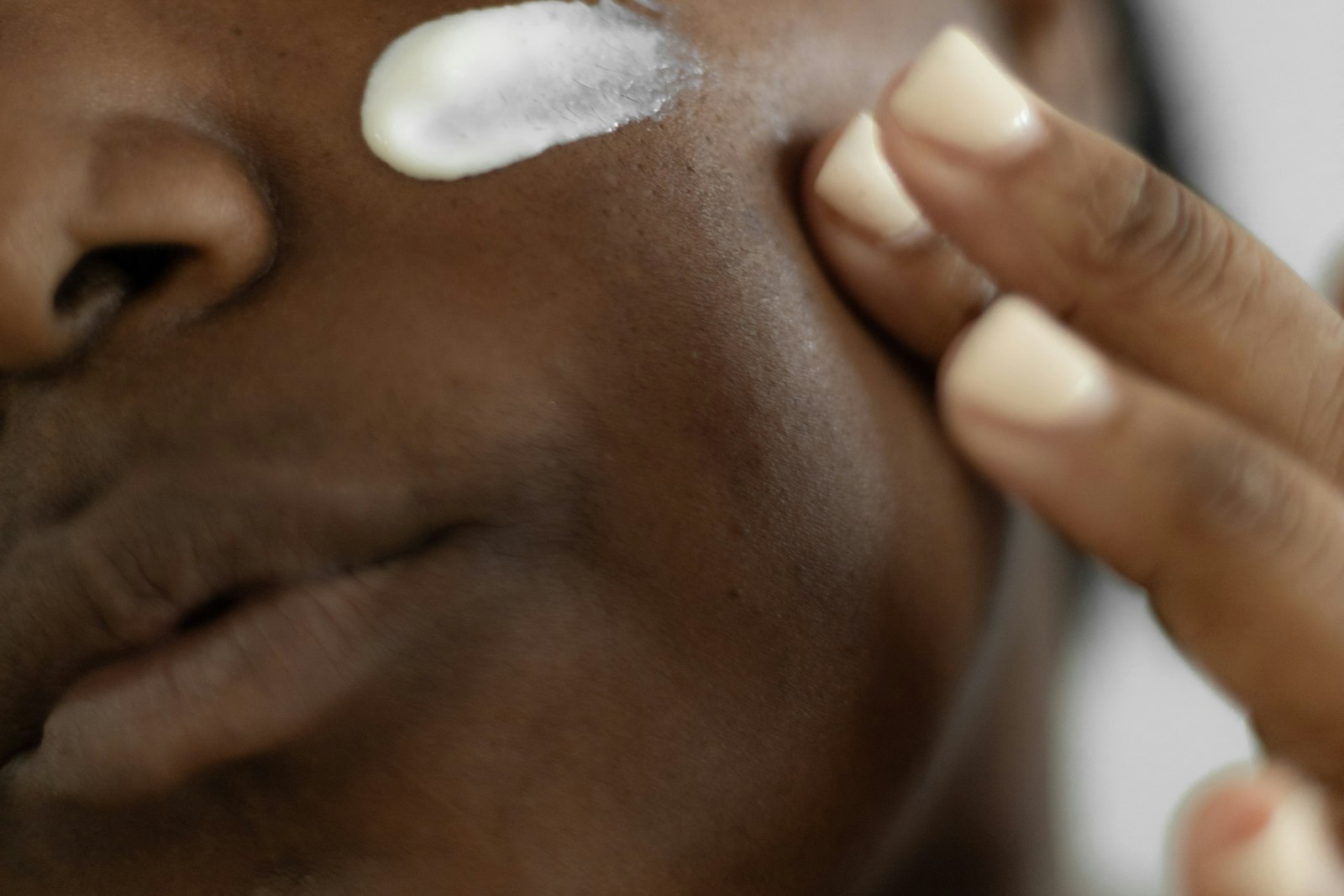 Close-up of a woman applying brightening cream to her cheek