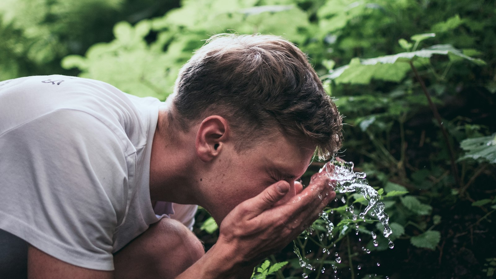Man splashing water on his face while washing