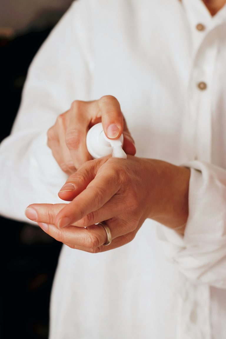 Hands pumping moisturising lotion from a white bottle